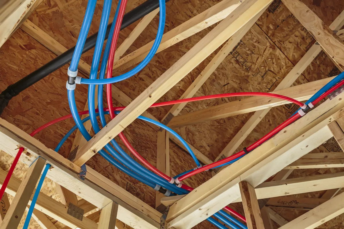 Red and blue PEX water lines run through attic trusses – Thinking About Navien Tankless Water Heater Installation in San Clemente? Start Here for San Clemente, CA homes